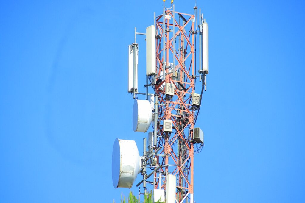 Telecommunications tower with microwave dishes and antennas against a clear sky, powered by standby generation in rural Kenya